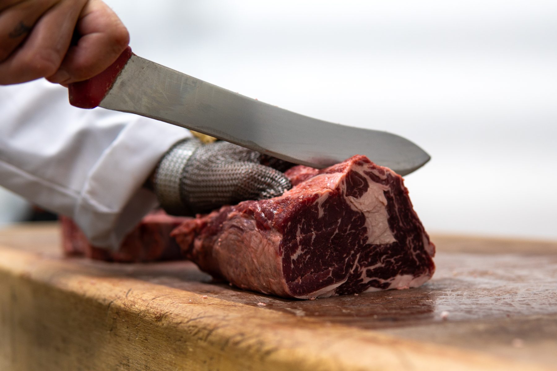 Ribeye being cut by hand on a wooden block